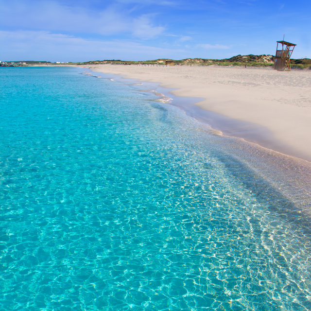 Blick vom Wasser auf Platja de Llevant mit hellem Sand und einem Bademeister Turm