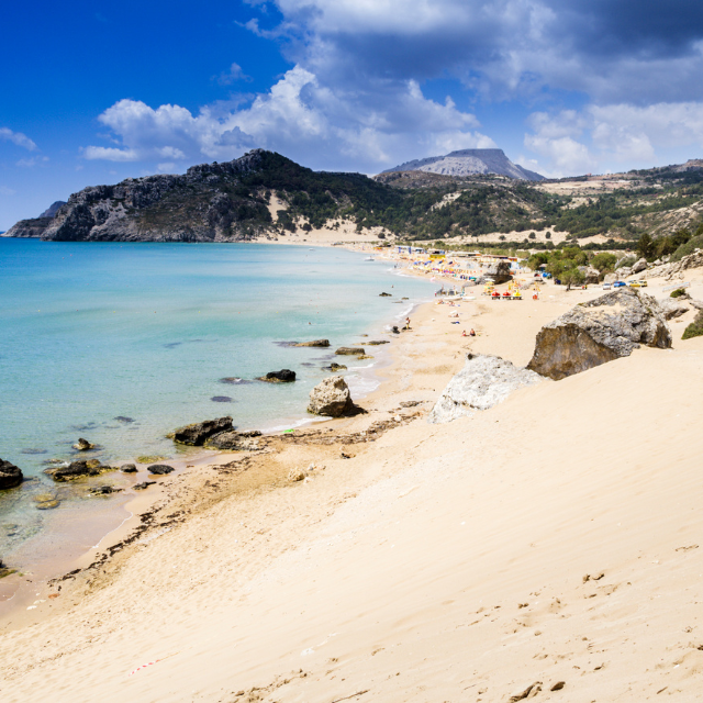 Weißer, feinsandiger Strand mit Bergen im Hintergrund