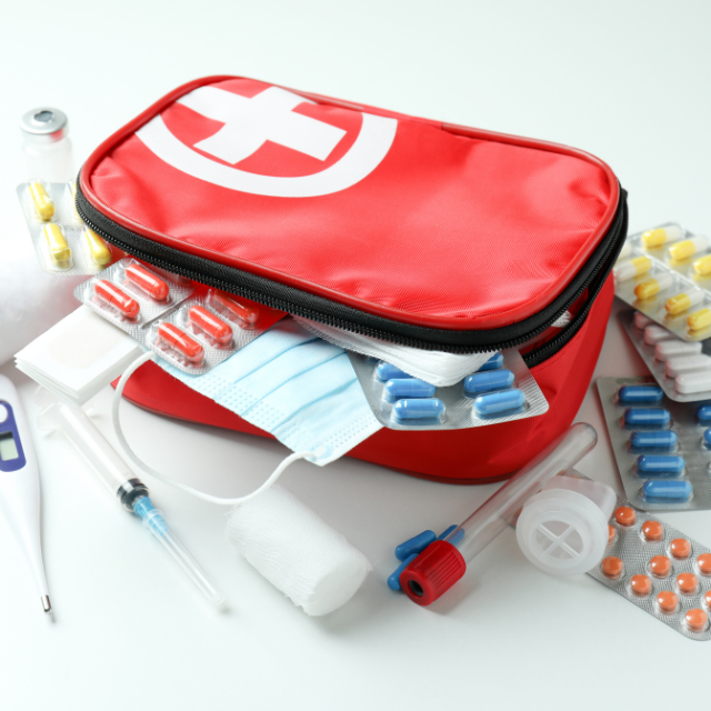 Geöffnete erste Hilfe Tasche mit vielen Medikamenten, Bandagen, Fieberthermometer und Mund-Nasen-Schutz