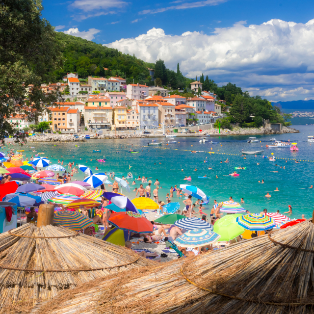 Belebter Strand in Istrien voller bunter Sonnenschirme