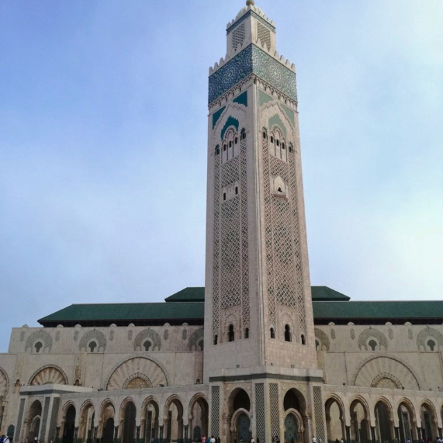 Blick auf die helle Moschee und de hohen Turm der Minarett. Dach und Mosaikverzierungen sind hellblau 