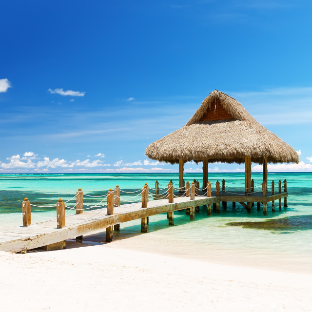 Strand-Pavillon mit Strohdach an einem Steg ins Wasser