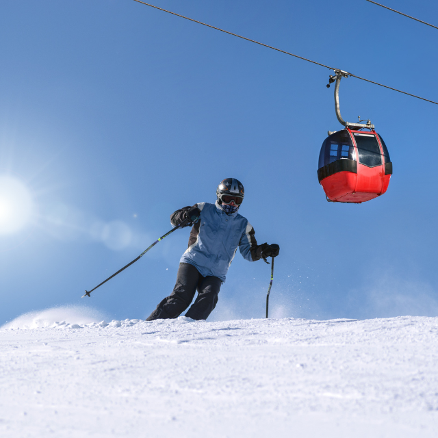 Skifahrer auf verschneitem Hang mit Seilbahn Gondel im Hintergrund