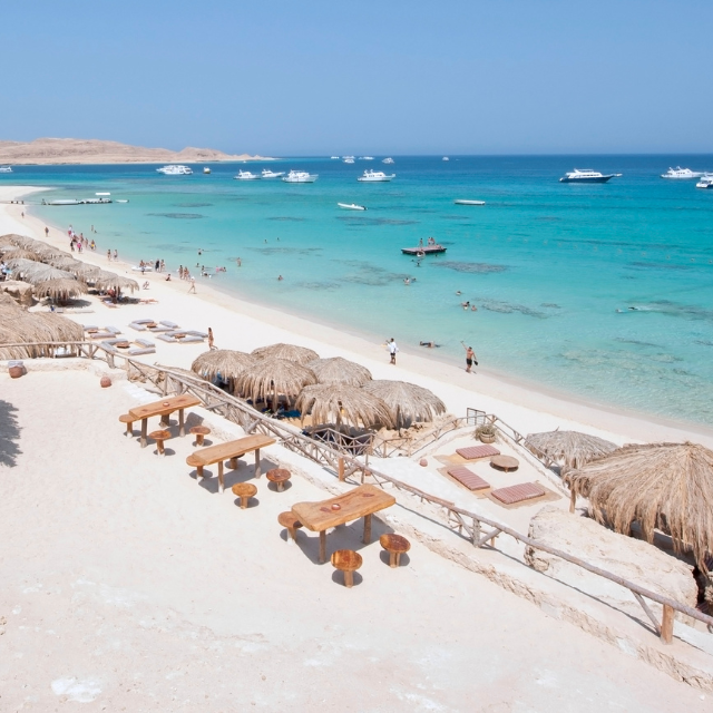 Giftun Islands Strand mit Booten im Wasser und vielen Strohschirmen und Hütten am Strand