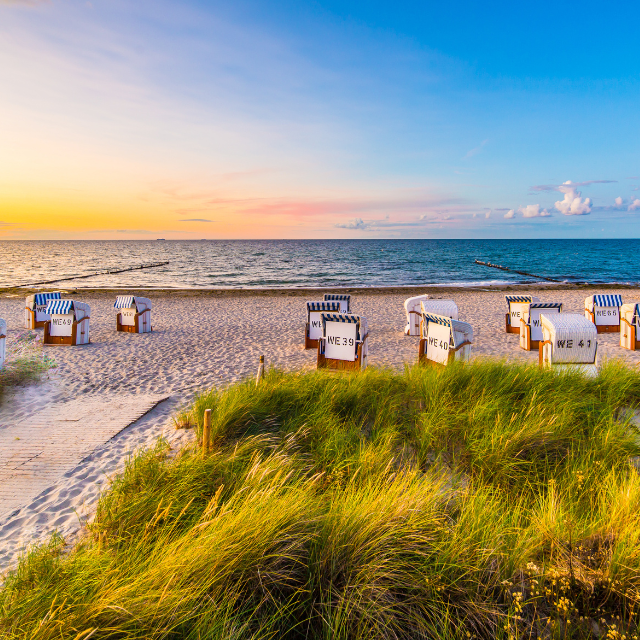 Strandkörbe am Ostseestrand in Abendstimmung mit Zugangsweg durch Dünen im Vordergrund