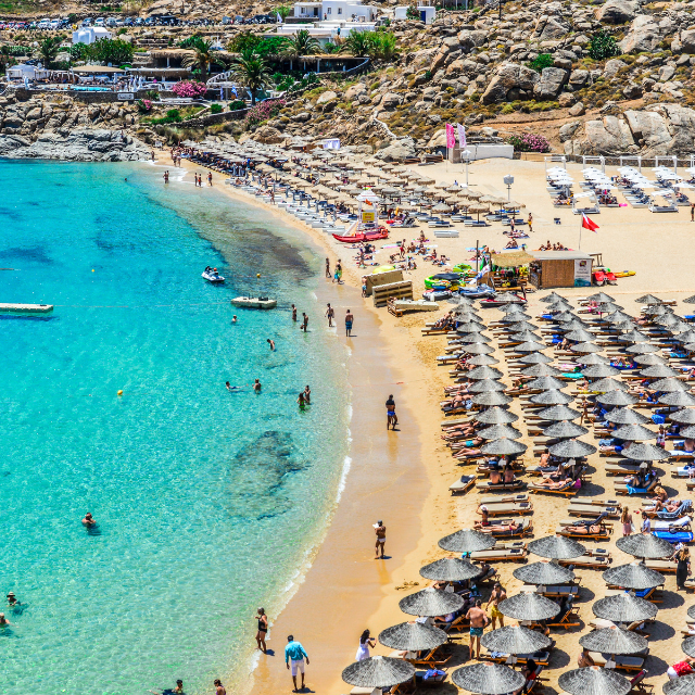 Blick entlang hellem Sandstrand Paradise Beach voller Liegen und Schirme