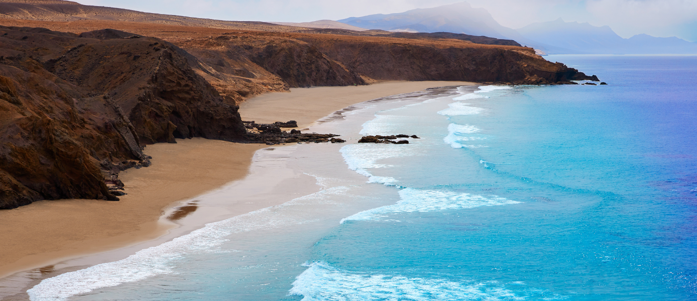 Heller Sandstrand mit hohen Klippen auf Fuerteventura