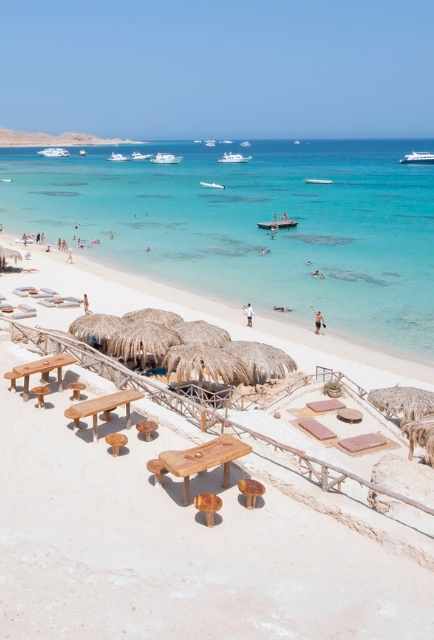 Giftun Islands Strand mit Booten im Wasser und vielen Strohschirmen und Hütten am Strand
