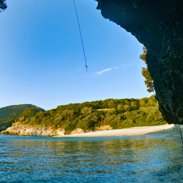 Blick aus Meereshöhle auf helle Kiesbucht Rovinia Beach